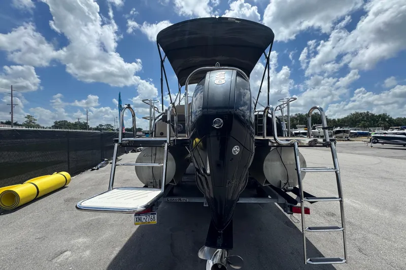 Slide: The Image of 2021 Harris Solstice 230 pontoon boat with outboard motor, docked under a sunny sky. - 65