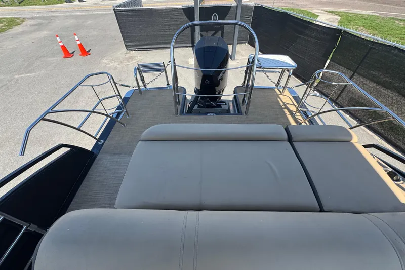Slide: The Image of 2021 Harris Solstice 230 boat deck with seating and railing, parked on pavement. - 27