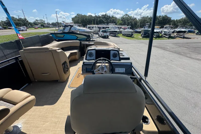 Slide: The Image of 2021 Harris Solstice 230 pontoon boat interior with helm and seating, parked outdoors. - 41