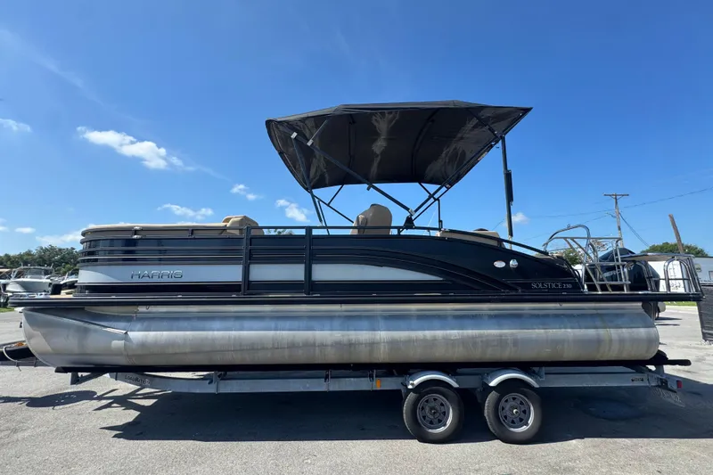 Slide: The Image of 2021 Harris Solstice 230 pontoon boat on trailer under clear blue sky. - 6