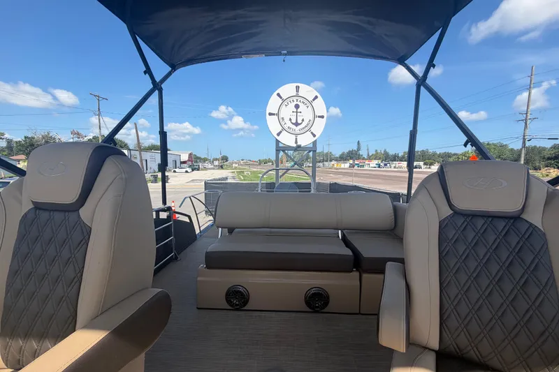 Slide: The Image of 2021 Harris Solstice 230 boat interior with beige seating and canopy under a clear sky. - 16