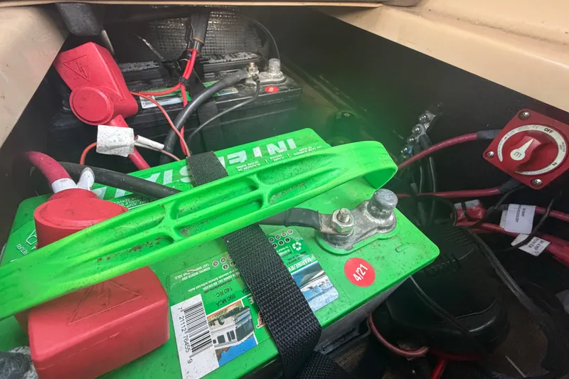 Slide: The Image of Battery compartment of a 2021 Harris Solstice 230 boat, featuring green marine battery and wiring. - 23