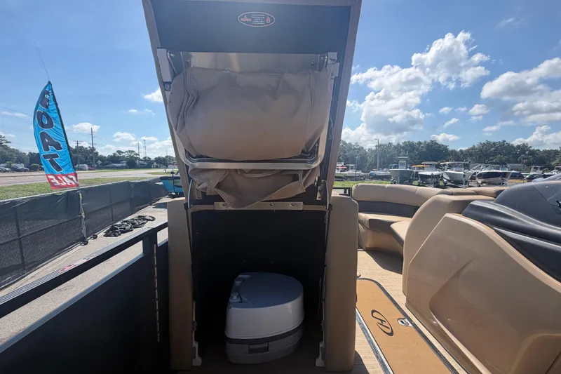 Slide: The Image of 2021 Harris Solstice 230 boat interior with portable toilet and seating under sunny skies. - 46