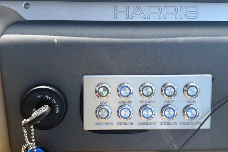 Slide: The Image of Control panel of a 2021 Harris Solstice 230 boat with labeled buttons and ignition key. - 55