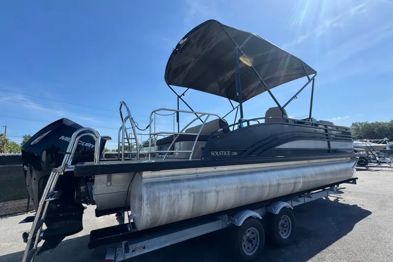 Slide: The Image of 2021 Harris Solstice 230 pontoon boat on trailer under clear blue sky. - 2