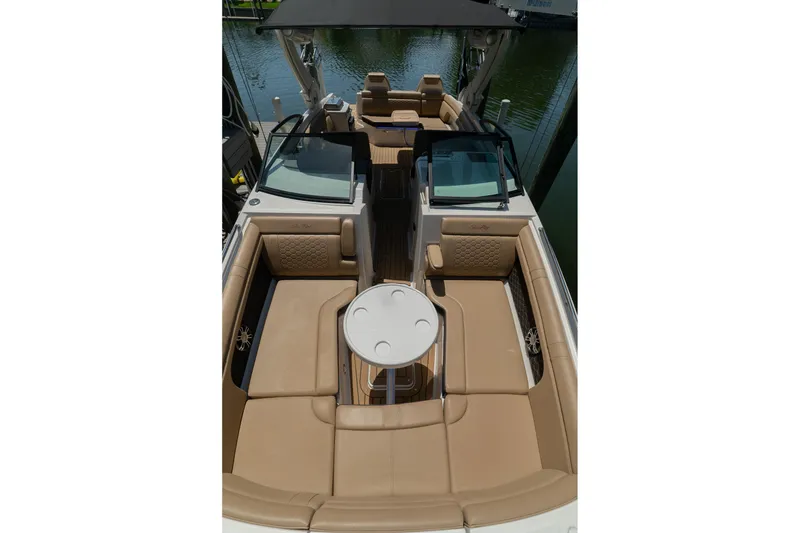 Slide: The Image of 2022 Sea Ray SDX 290 boat interior with tan seating and table, docked on water. - 59