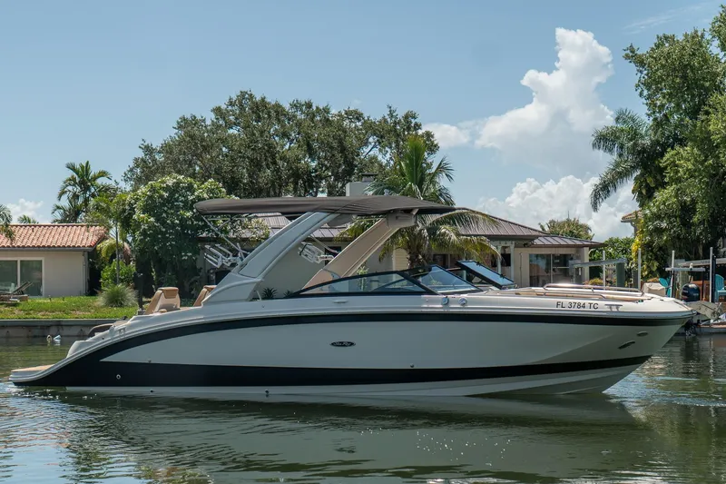 Slide: The Image of 2022 Sea Ray SDX 290 boat on a calm waterway, surrounded by lush greenery. - 2