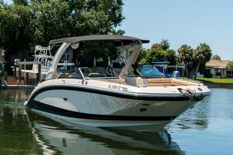 Slide: The Image of 2022 Sea Ray SDX 290 boat docked on a sunny day, surrounded by lush greenery. - 5