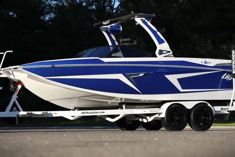 Slide: The Image of 2024 Tigé 22RZX boat in blue and white on a trailer, side view. - 2