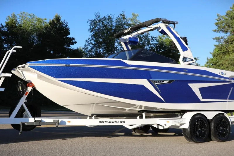 Slide: The Image of 2024 Tigé 22RZX boat in blue and white on a trailer, parked outdoors. - 8