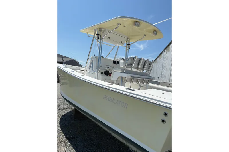Slide: The Image of 2008 Regulator 23 Forward Seating boat with T-top, parked outdoors under clear blue sky. - 16
