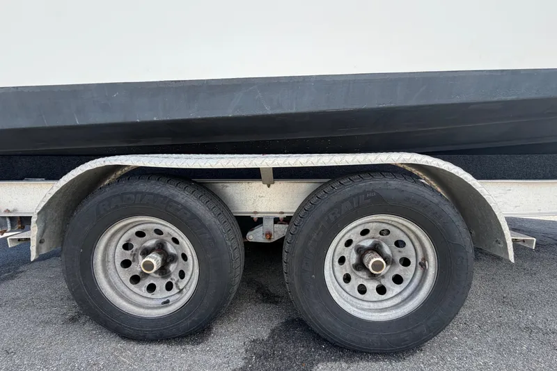 Slide: The Image of Trailer wheels of a 2006 Pro Sports 2550 BW boat on asphalt surface. - 80