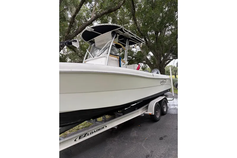 Slide: The Image of 2006 Pro Sports 2550 BW boat on trailer, parked under trees. - 2