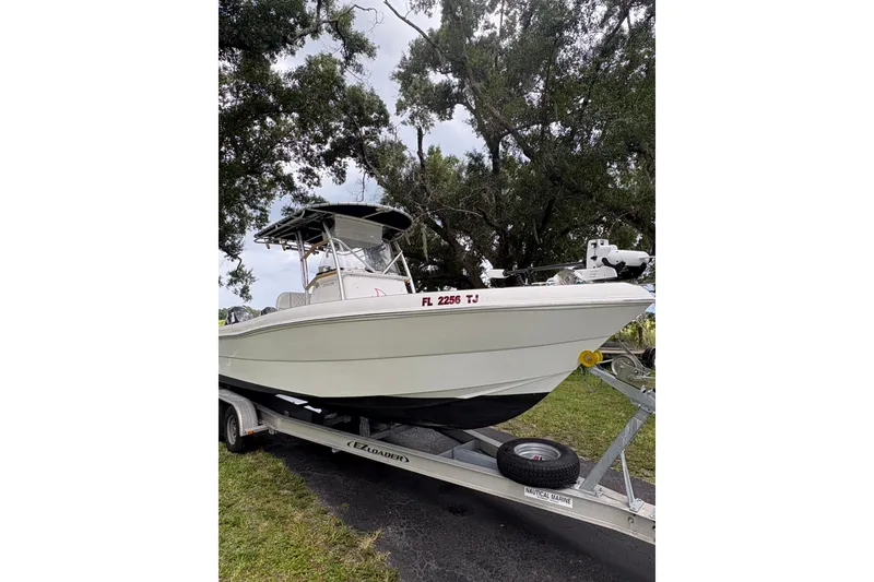 The Image of 2006 Pro Sports 2550 BW boat on trailer, parked outdoors under trees. - 0