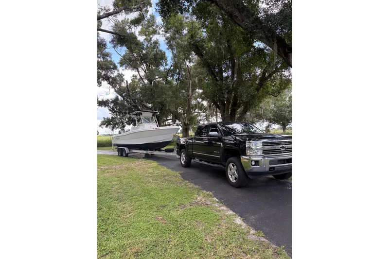 Slide: The Image of Black truck towing a 2006 Pro Sports 2550 BW boat on a tree-lined road. - 25