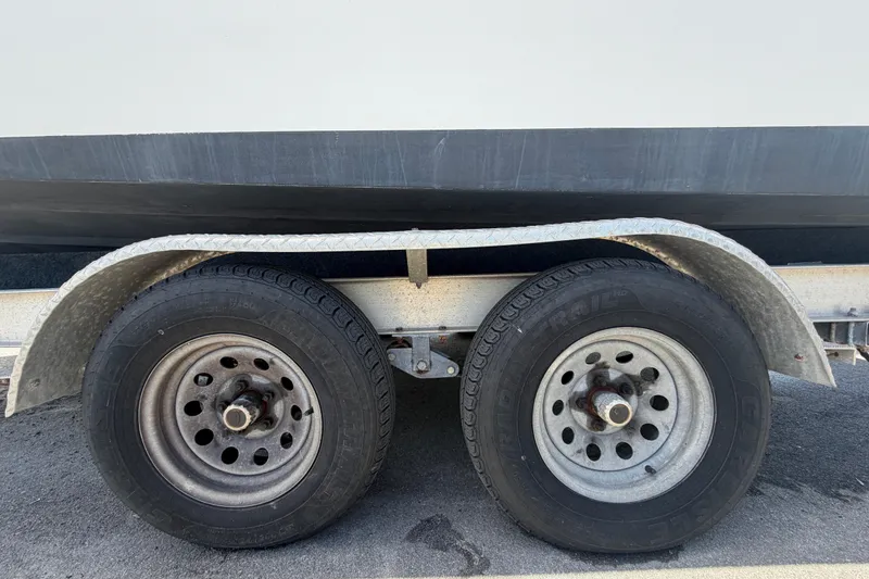 Slide: The Image of Trailer wheels of a 2006 Pro Sports 2550 BW boat on asphalt surface. - 81