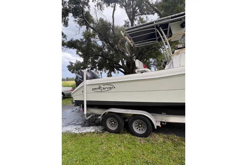 Slide: The Image of 2006 Pro Sports 2550 BW boat on trailer, parked on grass under trees. - 24