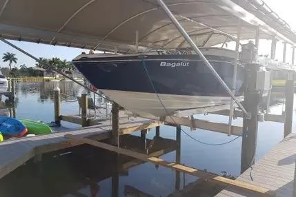 Slide: The Image of 2016 Yamaha Boats 242 Limited S E-Series on dock lift, under canopy, near waterfront. - 4