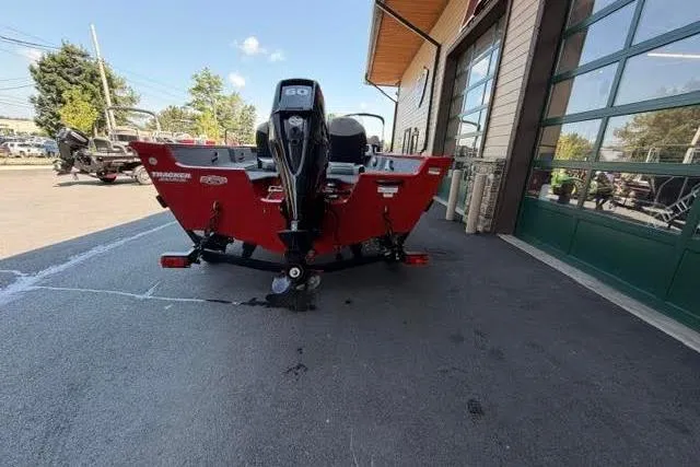 Slide: The Image of 2017 Tracker Pro Guide V-16 SC boat with outboard motor, parked outside a building. - 10