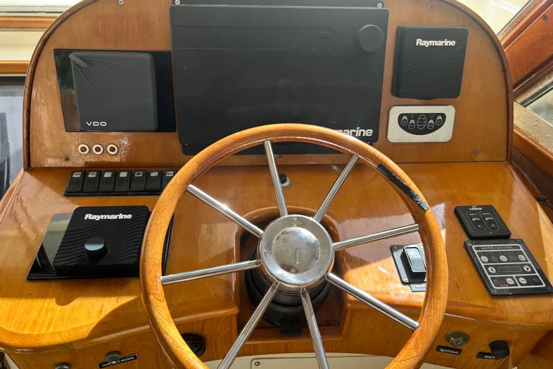 Slide: The Image of 2007 Legacy EXPRESS CRUISER helm with wooden steering wheel and Raymarine navigation equipment. - 10