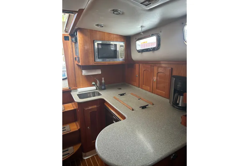 Slide: The Image of 2007 Legacy EXPRESS CRUISER kitchen with wooden cabinets, microwave, and countertop. - 26