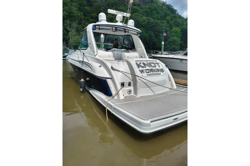 Slide: The Image of 2005 Formula 48 Yacht docked, featuring "Knot Working" nameplate, surrounded by lush greenery. - 2
