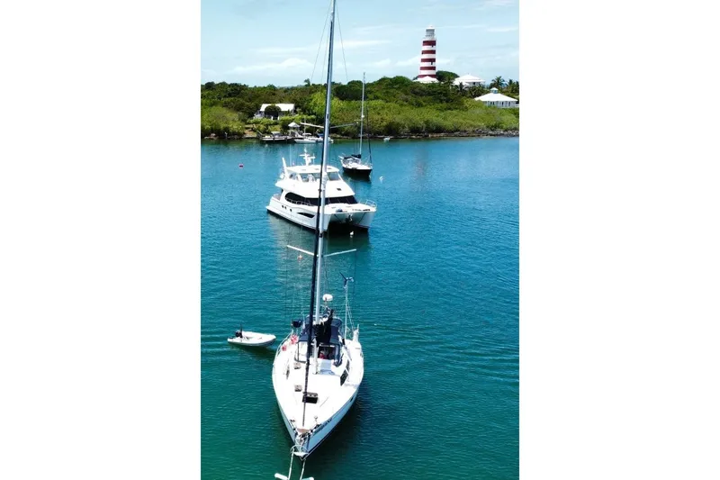 Slide: The Image of Sailboats anchored in clear blue water near a lighthouse, featuring a 1994 Bass Hunter Passage. - 2