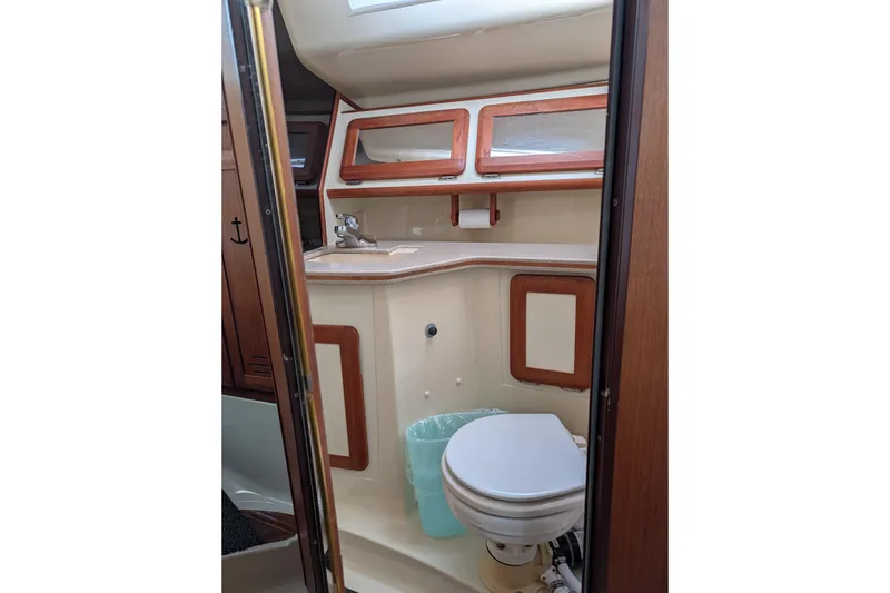 Slide: The Image of 1994 Bass Hunter Passage boat bathroom with sink, toilet, and wooden cabinetry. - 14