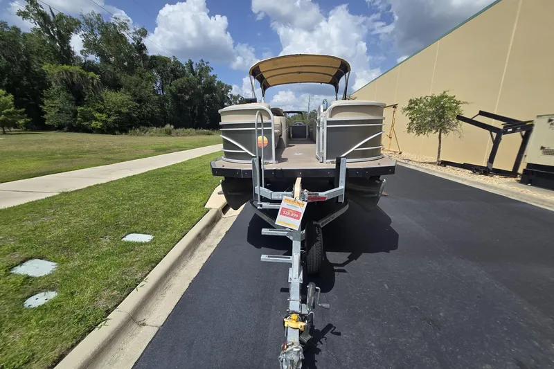 Slide: The Image of 2021 Sun Tracker Party Barge 24 DLX on trailer, parked outdoors under a cloudy sky. - 3