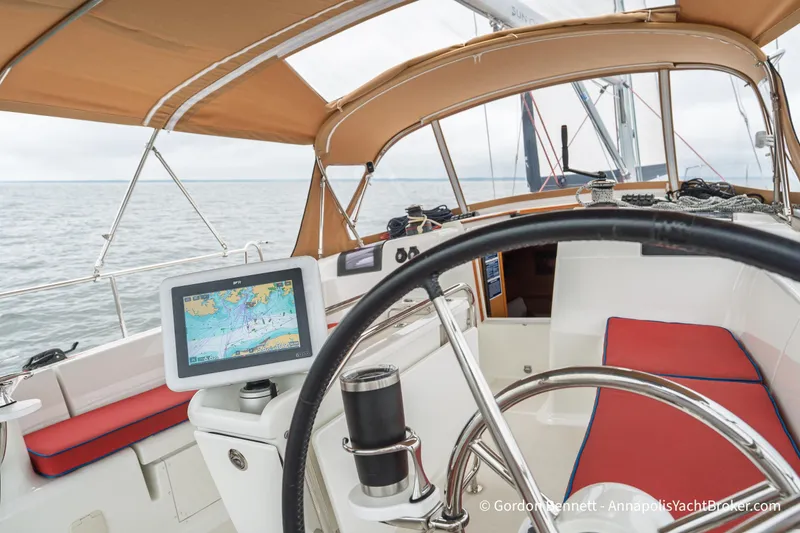 Slide: The Image of Cockpit of 2015 Jeanneau Sun Odyssey 439 sailboat with navigation display and red cushions. - 35