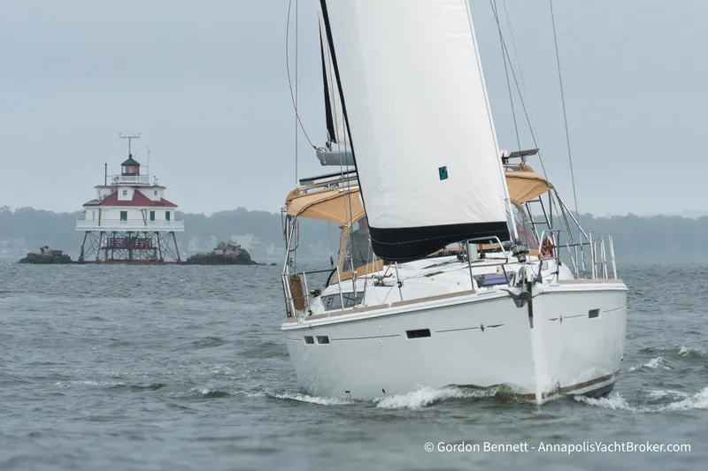 Slide: The Image of Sailing yacht Jeanneau Sun Odyssey 439, 2015 model, near a historic lighthouse on a cloudy day. - 6