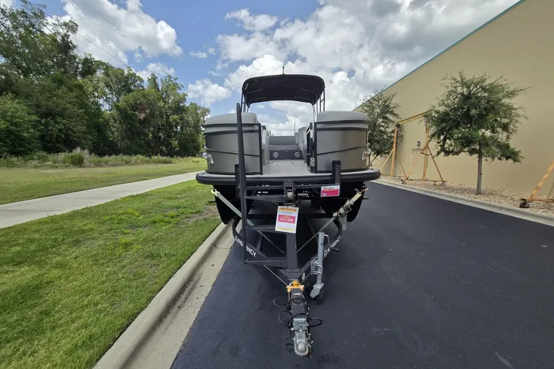 Slide: The Image of 2019 Regency 230 LE3 Sport pontoon boat on trailer, parked outdoors. - 2