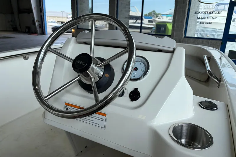 Slide: The Image of 2024 Boston Whaler 130 Super Sport steering console with stainless steel wheel and gauges. - 18