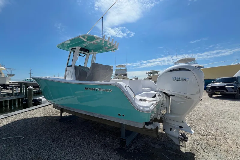 Slide: The Image of 2024 Sportsman Heritage 231 Center Console boat with Yamaha engine, docked under clear blue sky. - 2