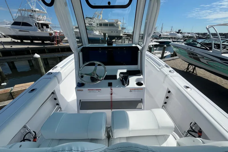 Slide: The Image of 2024 Sportsman Heritage 231 Center Console boat interior at marina, showcasing helm and seating. - 9