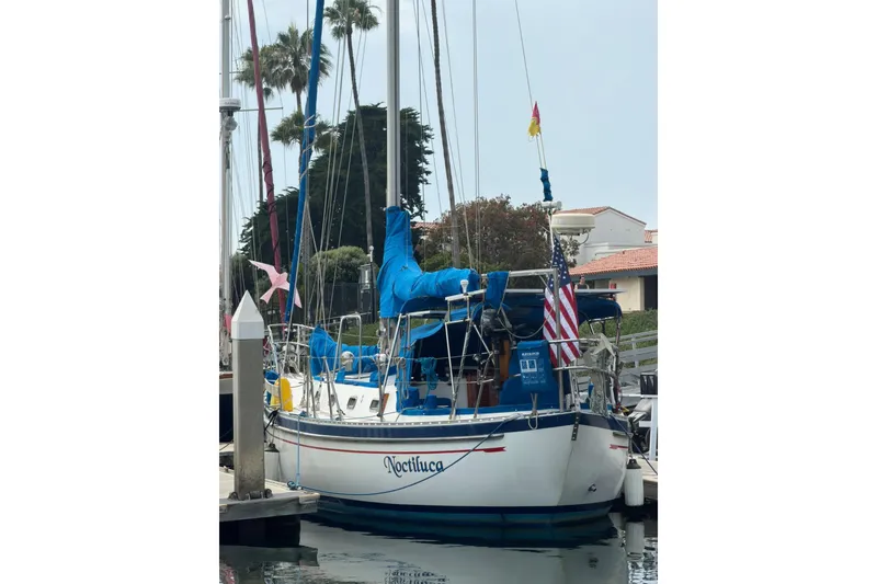 Slide: The Image of 1989 Tayana Vancouver 42 sailboat docked, featuring blue covers and American flag. - 15