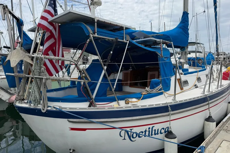 Slide: The Image of 1989 Tayana Vancouver 42 sailboat docked, featuring blue covers and American flag. - 14