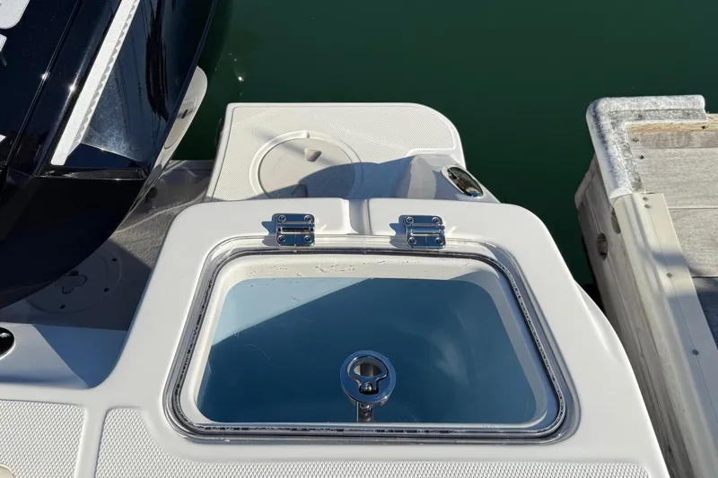 Slide: The Image of 2025 Boston Whaler 250 Outrage boat detail with livewell and engine, docked by water. - 19