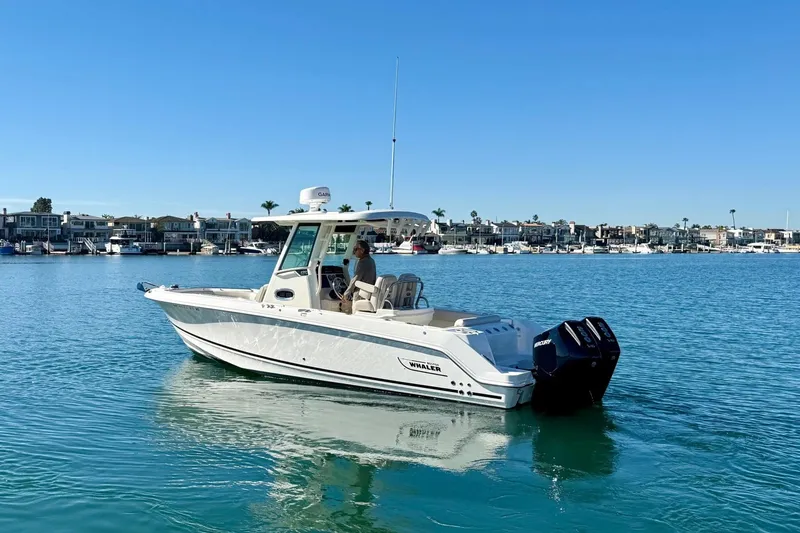 Slide: The Image of 2025 Boston Whaler 250 Outrage boat on calm water, coastal background. - 4