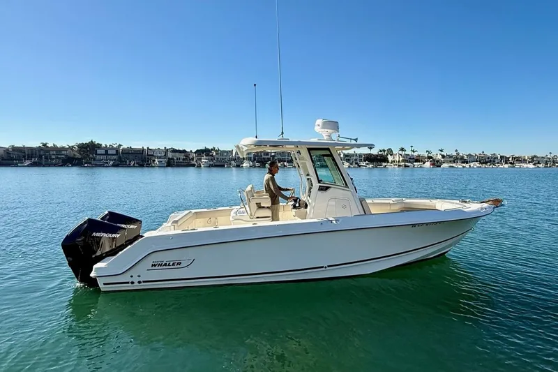 Slide: The Image of 2025 Boston Whaler 250 Outrage boat on calm water, clear sky background. - 1