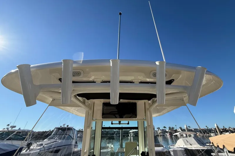 Slide: The Image of 2025 Boston Whaler 250 Outrage boat with rod holders, marina background, sunny day. - 16