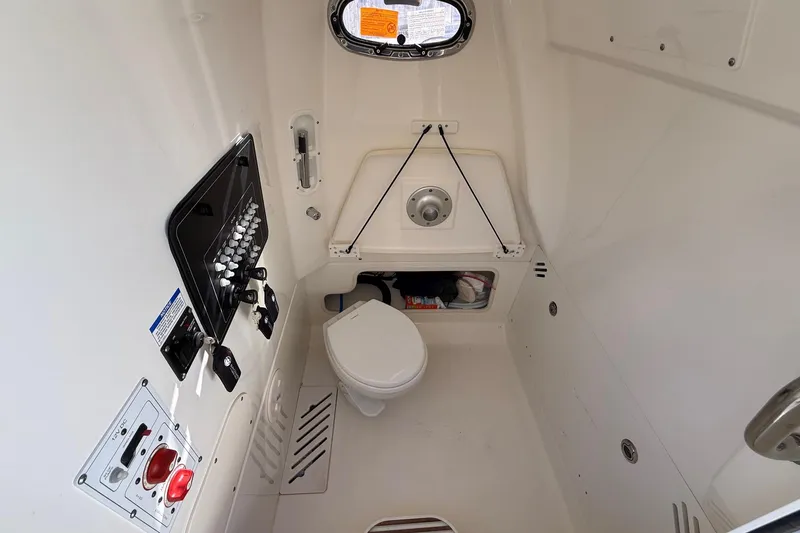 Slide: The Image of Interior of 2025 Boston Whaler 250 Outrage boat, featuring a compact marine toilet. - 35