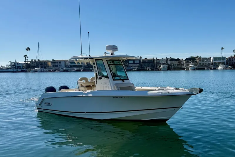 Slide: The Image of 2025 Boston Whaler 250 Outrage boat on calm water, with coastal background. - 7