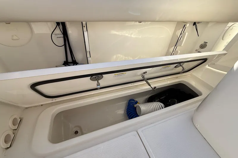 Slide: The Image of 2025 Boston Whaler 250 Outrage storage compartment with hoses and equipment. - 24