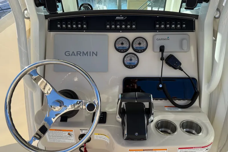 Slide: The Image of 2025 Boston Whaler 250 Outrage dashboard with Garmin navigation and controls. - 28