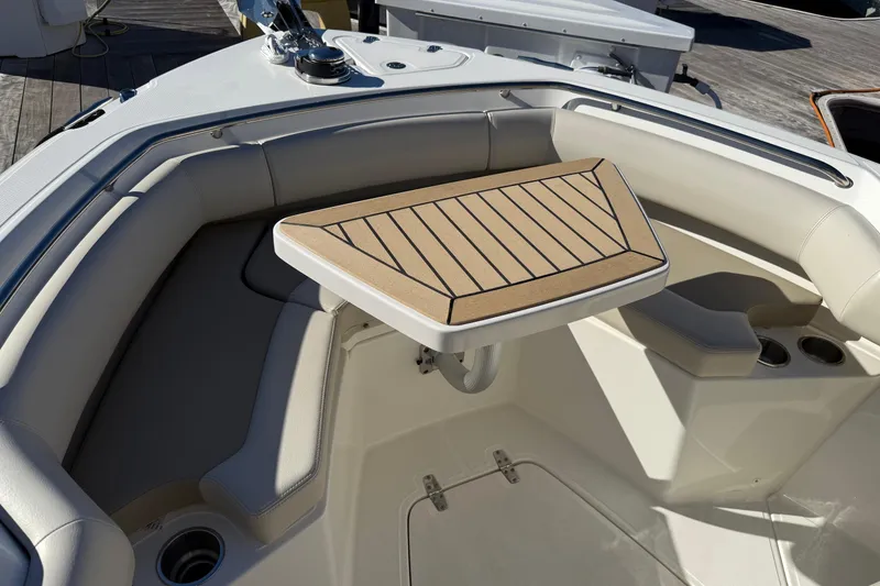 Slide: The Image of 2025 Boston Whaler 250 Outrage boat interior with cushioned seating and a wooden table. - 40