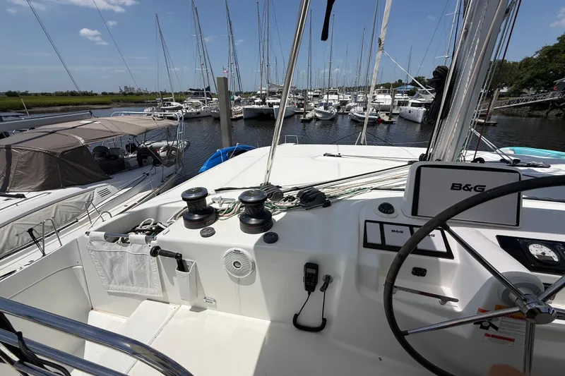Slide: The Image of Cockpit view of 2021 Lagoon 46 catamaran in marina, featuring steering wheel and navigation equipment. - 21