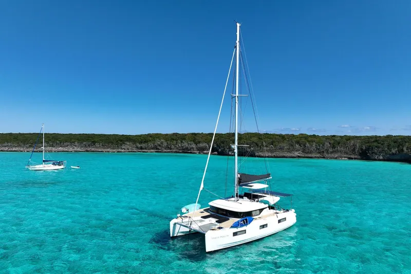 Slide: The Image of 2021 Lagoon 46 catamaran anchored in clear turquoise waters under a bright blue sky. - 3