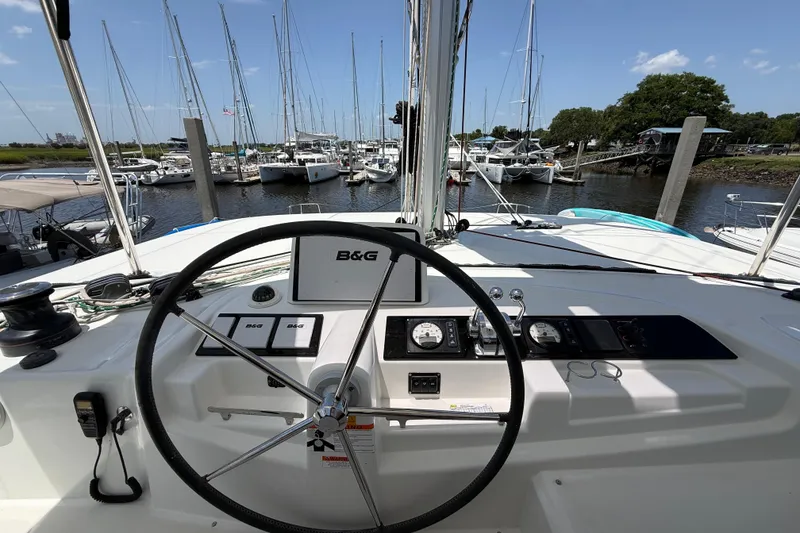 Slide: The Image of Steering wheel and controls of a 2021 Lagoon 46 catamaran docked at a marina. - 16