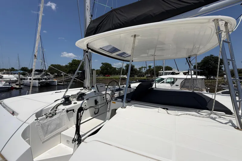Slide: The Image of 2021 Lagoon 46 catamaran helm station with modern controls and canopy, docked at marina. - 12